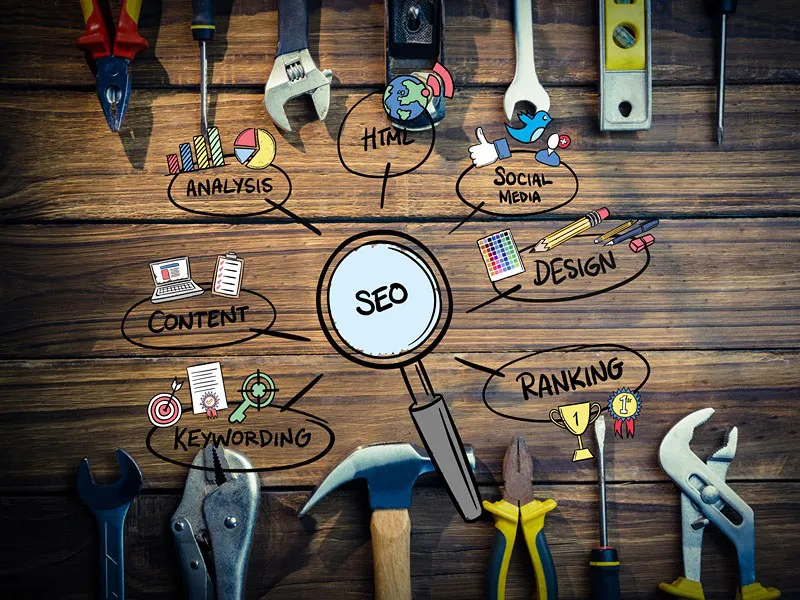 عبارت SEO داخل ذره‌بین و ابزارآلات در دو طرف آن قرار گرفتند. در دایره‌های مشکی اطراف ذره‌بین، مفاهیم مرتبط با سئو را می‌بینید.